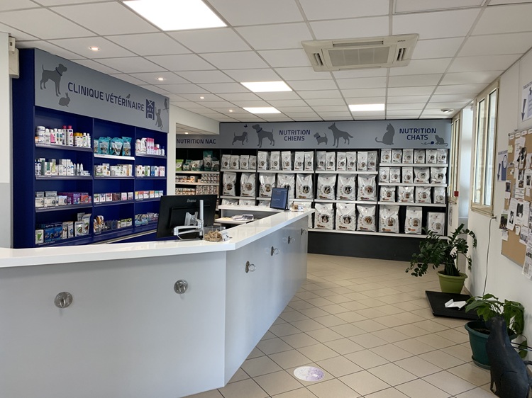 Accueil de la clinique XOVET - Le comptoir, les médicaments et soins indispensables à l'arrière du comptoir et le linéaire de Pet Food