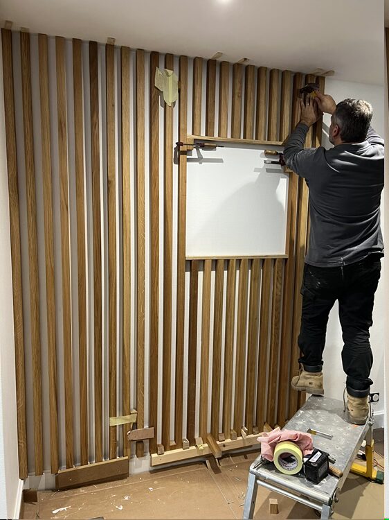 Habillage du mur d'accueil clients avec des tasseaux de bois avec encart laissé pour le logo