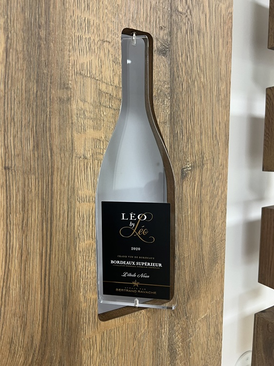 Zoom sur les meubles dessinés et fabriqués sur mesure - Bouteille plexi en rotation sur axe vertical avec mise en place d'une étiquette fabriquée par Nacara